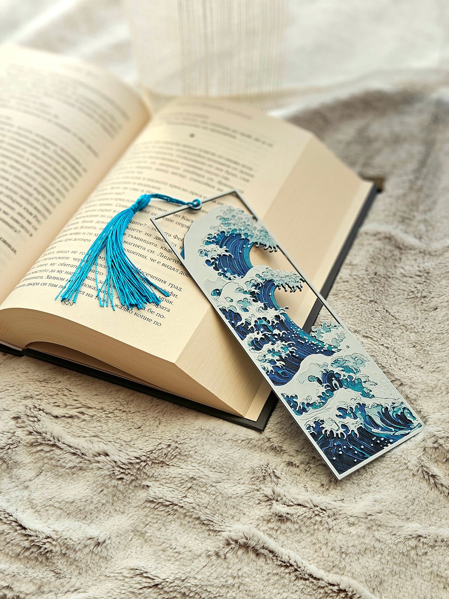 Open book with a decorative bookmark featuring a wave design on a textured surface.
