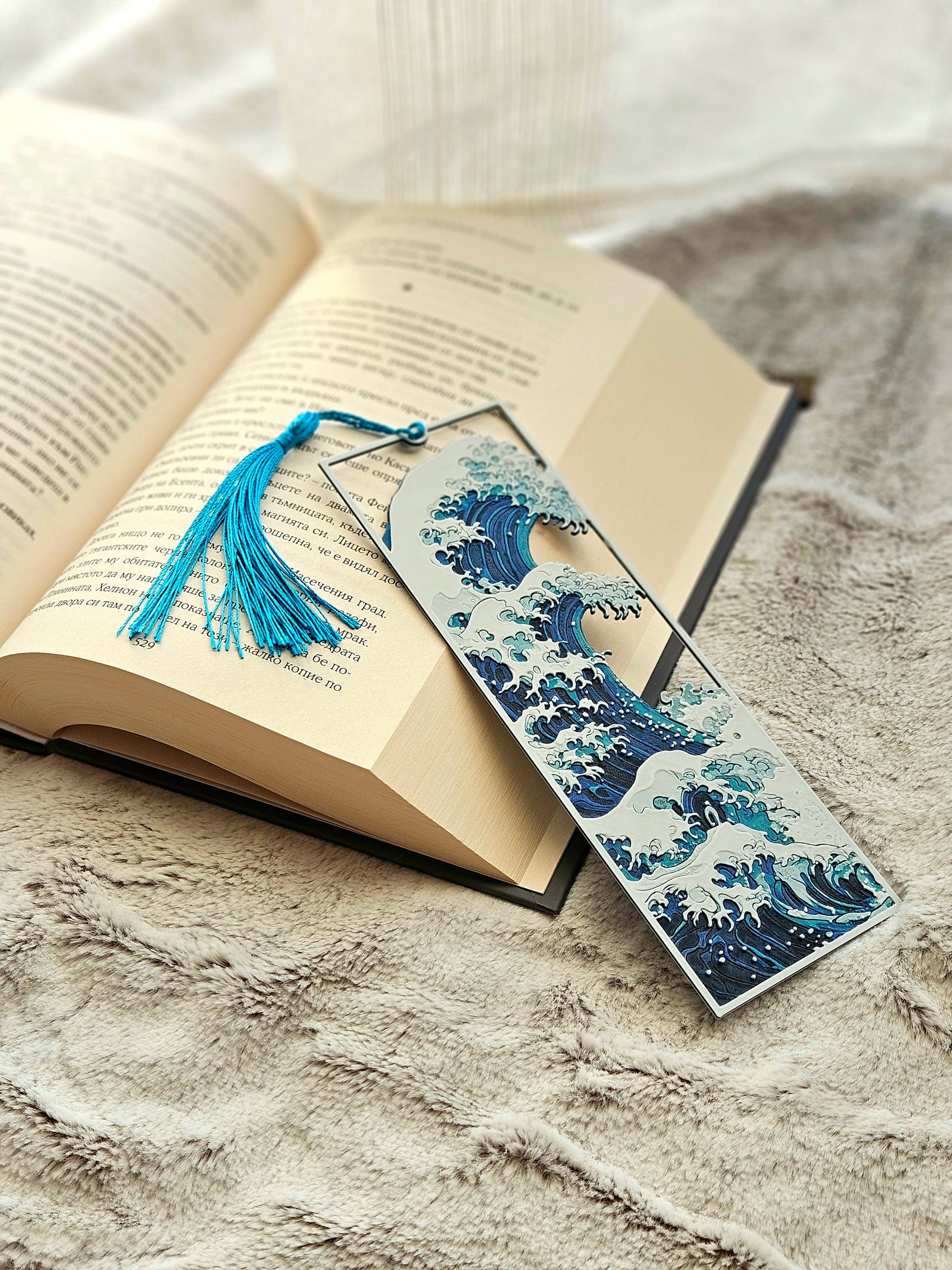 Open book with a decorative bookmark featuring a wave design on a textured surface.